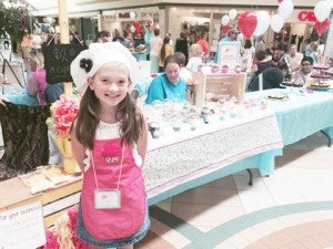 Kayleigh Sadler, 9, of Groves poses in front of her business, Cupcake Concoctions, during the fourth annual Kids, Inc. entrepreneur program at Central Mall Saturday.