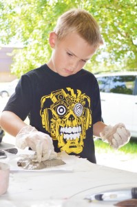 Ian Koushan, 8, of Bridge City decorates his freeform concrete cross with sea glass during the annual Art Smart kids' summer camp at the Texas Artists Museum in Port Arthur Tuesday.