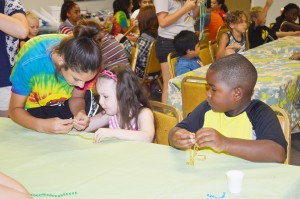 Volunteer Jamye Nchugh, left, shows Art Smart 2015 students Hollierose Justice, 5, of Groves and Bryson Greene, 6, of Port Arthur how to make a "bead puppy" at the Texas Artists Museum in Port Arthur Tuesday.