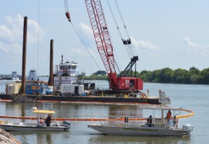 Employees with OMI Environmental Solutions keep watch over a boom placed around the capsized tugboat Louise in the Intracoastal waterway in Port Arthur on Monday. Mary Meaux/The News