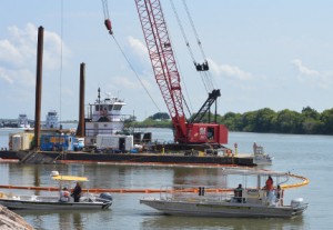 Employees with OMI Environmental Solutions keep watch over a boom placed around the capsized tugboat Louise in the Intracoastal waterway in Port Arthur on Monday.  Mary Meaux/The News