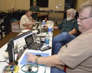 Wayne Meaux, right, checks settings on a model train along with Jeff Hamilton and George Barnes as Randy Williamson, back, works a remote control in a behind the scenes photo during Model Trains in (Loco)motion at Thursday at Effie and Wilton Public Library in Port Neches on Thursday. The men are members of East Texas and Gulf Rail Modelers Association, Beaumont, Tx. Mary Meaux/The News