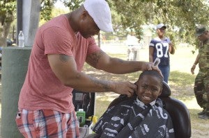 Shawn Collins, left, gives a free haircut to Kenery Prevost during Stop the Violence Men's March at Barbara Jacket Park in Gilliam Circle on Saturday. Mary Meaux/The News