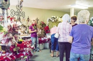 Mondi Hebert, niece of Harris Florist owner Carolyn Harris, left, greets each visitor Wednesday morning with a dozen roses during the 21st annual Good Neighbor Day rose give-a-way at Harris Florist in Nederland.
