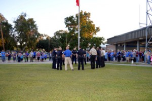 Port Neches Police officers surround the flagpole at the vacant fire station while surrounded by community members during See You At the Station on Wednesday. Mary Meaux/The News