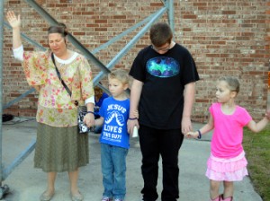 Alicia Gramza, left, and children Aiden, Zach and Zoey, offer prayers police officers during See You At the Station in Port Neches on Wednesday. Mary Meaux/The News 