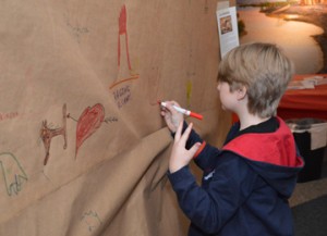 Lucas Howard, 7, of Nederland, traces his handprint onto paper while learning about cave drawings during a free family day at the Museum of the Gulf Coast on Saturday. Children and families learned about archeology and performed paleontology digs during the event.  Mary Meaux/The News