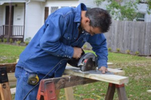 Texas Gas Service employee Shannon O’Connor saws wood for a wheelchair ramp to benefit a Groves couple on Thursday. Mary Meaux/The News 