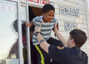 Andrew Jackson, 7, left, emerges from the Bridge City Fire Department Children’s Fire Safety House with the assistance of Port Arthur Firefighter Tyler Barbay during a Port Arthur fire prevention week event at the Robert A. “Bob” Bowers Civic Center on Monday. Mary Meaux/The News