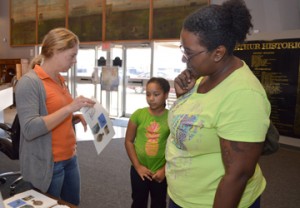 Museum of the Gulf Coast Education Coordinator Stephanie Harren, left, tells Crystal Coleman, right, and Salem Coleman, about the Free Family Fun Day events where children learned about archeology and paleontology Saturday. Mary Meaux/The News