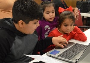 Jesus Hermoso, left, shows Valeria Gonzalez, 6, and Guadalupe Sanchez, 2, how to log onto a computer at the Port Arthur Public Library on Monday. Children were at the library learning how to download books during a program. Mary Meaux/The News 