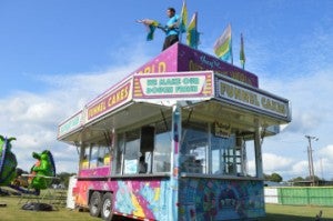Lowery Carnival Company employee Demeterius Dunn places colorful flags atop a food trailer at Lion’s Park in Groves on Wednesday.  Mary Meaux/The News