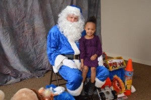   Ka’liyah Thomas, 4, poses with Santa Claus during the Port Arthur Police Blue Santa toy distribution at the Robert A. “Bob” Bowers Civic Center on Monday.    Mary Meaux/The News 