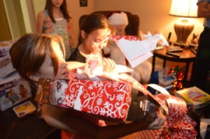 Cadence Clark, left, unwraps an early Christmas gift at her grandparent’s home in Beauxart Gardens Wednesday night. Mary Meaux/The News