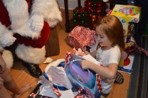 MaKayla Clark, 6, unwraps an early Christmas gift at her grandparent’s home in Beauxart Gardens Wednesday night. Mary Meaux/The News 