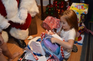 MaKayla Clark, 6, unwraps an early Christmas gift at her grandparent’s home in Beauxart Gardens Wednesday night. Mary Meaux/The News