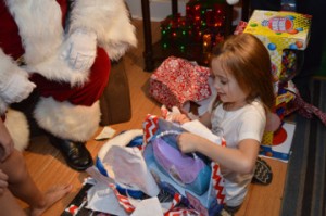 MaKayla Clark, 6, unwraps an early Christmas gift at her grandparent’s home in Beauxart Gardens Wednesday night. Mary Meaux/The News 