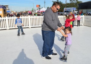 Charles Meaux Jr. helps his daughter, Josette “Josie” Meaux, 2 1/2, “ice” skate during Christmas on the Avenue in Nederland on Saturday. Mary Meaux/The News