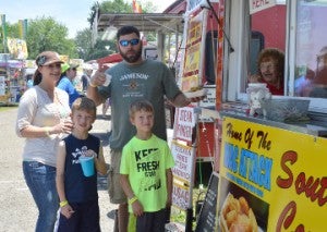 Chris Manuel, right, grabs a snack from Southern Comfort Catering food booth as his wife, Amy, and sons, Alex and Gauge, look on during Port Neches RiverFest on Saturday. Mary Meaux/The News