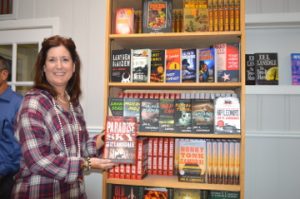 Debbie Plaia, executive director of the Port Neches Chamber of Commerce, holds a copy of a book written by East Texas author John R. Lansdale during the ribbon cutting at Fleur Fine Books in Port Neches on Wednesday. Lansdale will hold a book signing at the bookstore from 4 to 6 p.m. Saturday. Mary Meaux/The News