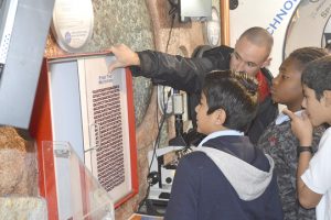 Brian Armstreet, a Flint Hill employee and TAME volunteer, instructs DeQueen students at one of the science exhibits aboard the trailer. (Lorenzo Salinas/ The News)