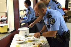 Port Arthur Police Department officers serve themselves some white rice on top of their chicken and sausage gumbo. (Lorenzo Salinas/The News)